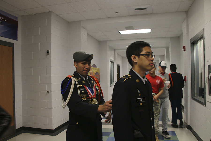 Junior Mellser Aguilar helps Freshmen Den Ha with his uniform. 