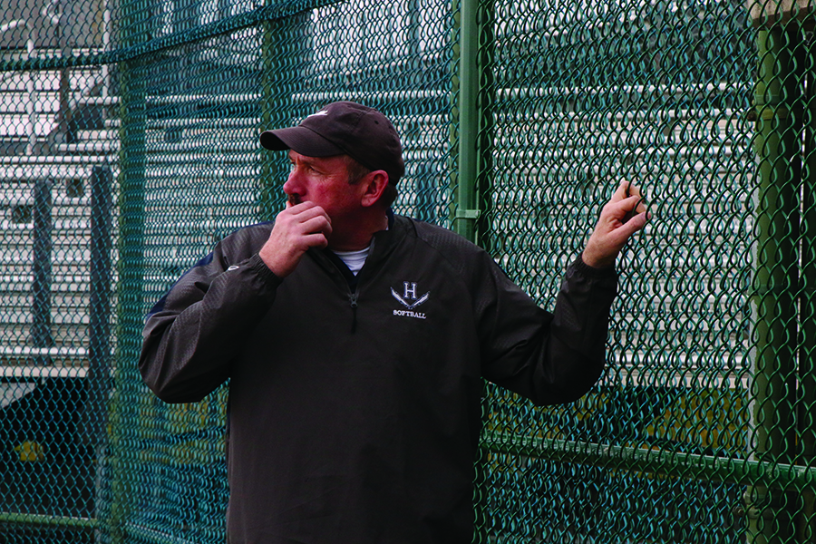 Head coach Scott Sheets stands on the fence and looks out as his team prior to the start of practice. 