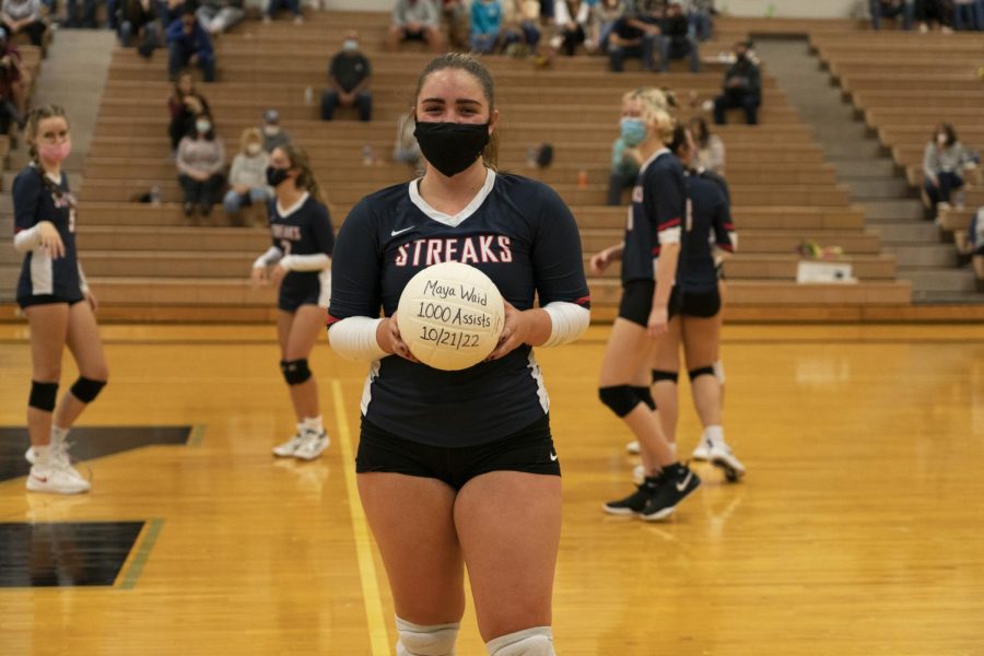 Senior Maya Waid poses with her 1,000 assists volleyball during the second set.