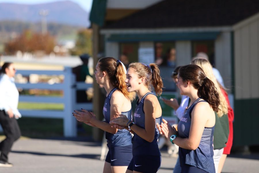 Members of the girls cross country team cheer on the boys team as they run in their race. 
