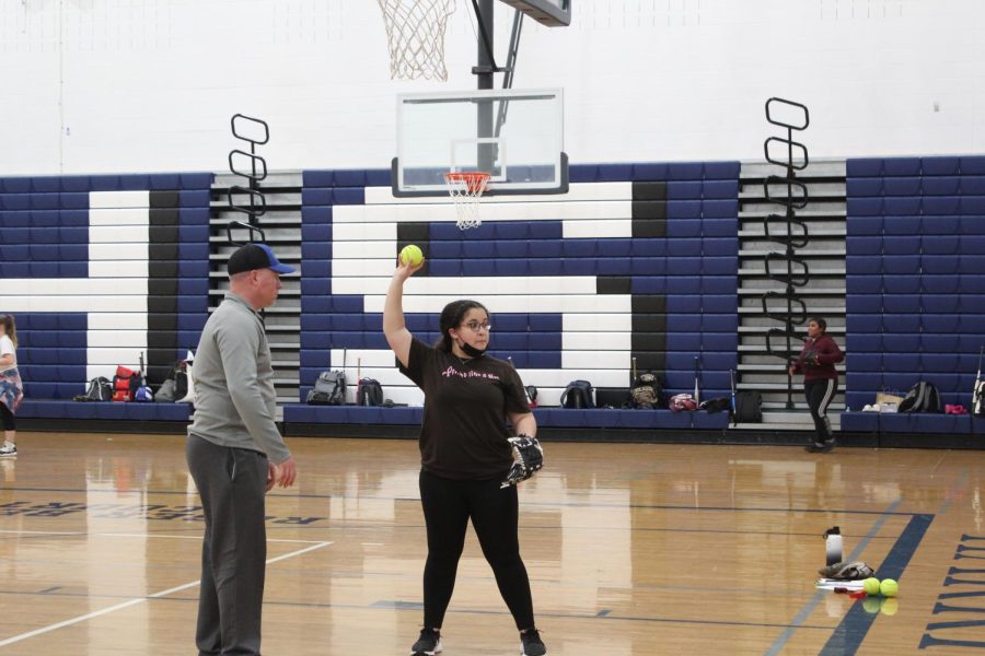 Sophomore Logan Whiting is in instructed on how to throw a softball.