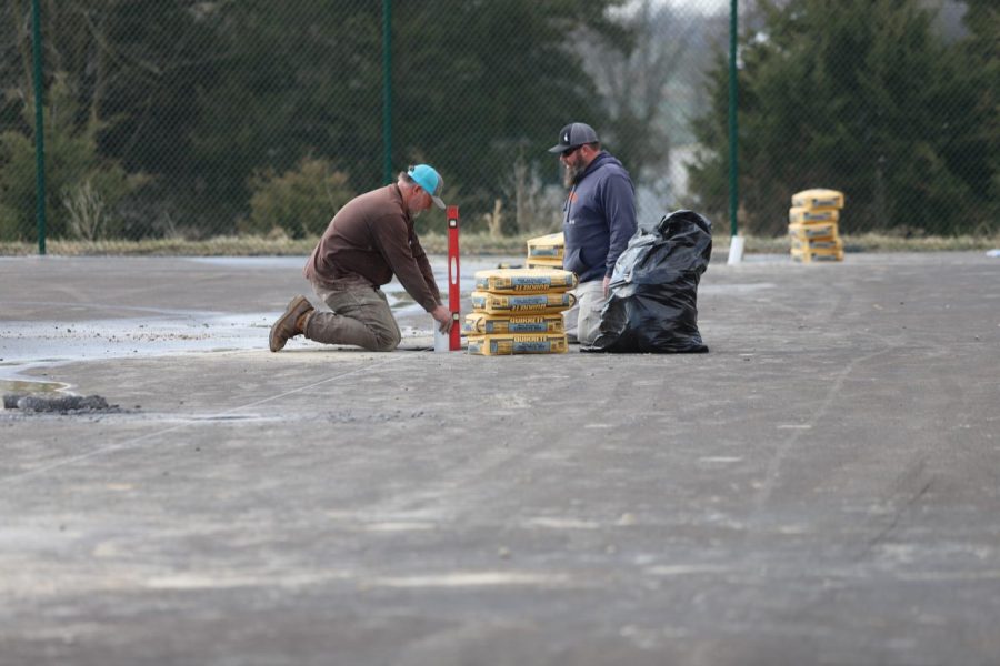 Workers use levels to drill holes and place cement for nets.