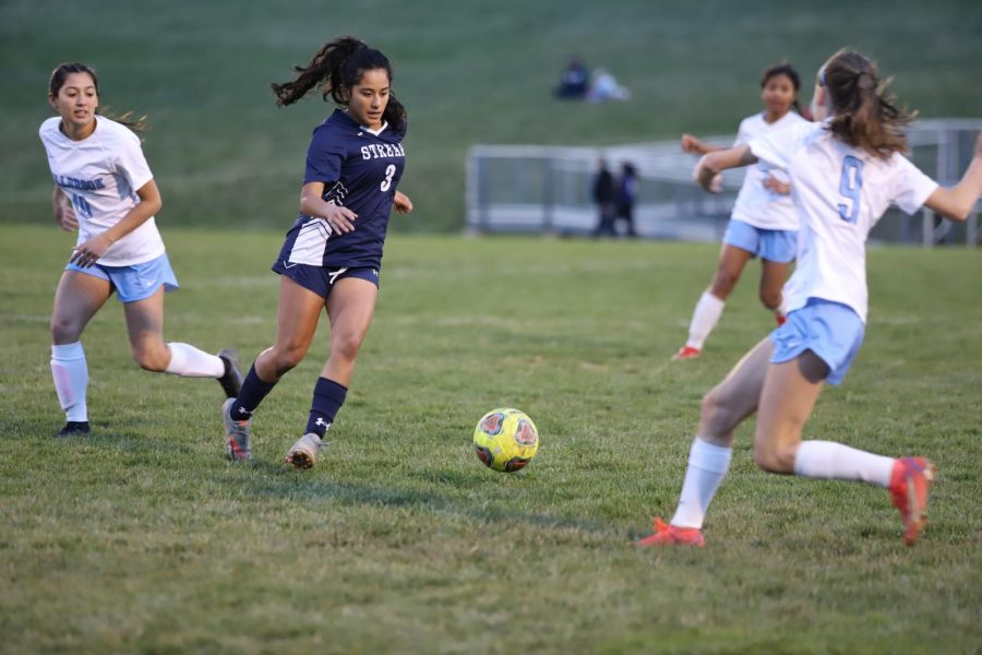 Sophomore Esmeralda Cardoso Rodriguez dribbles the ball between defenders. 