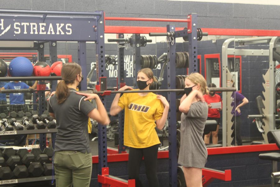 Coach Brubaker showing the girls how to properly do weighted squats.
