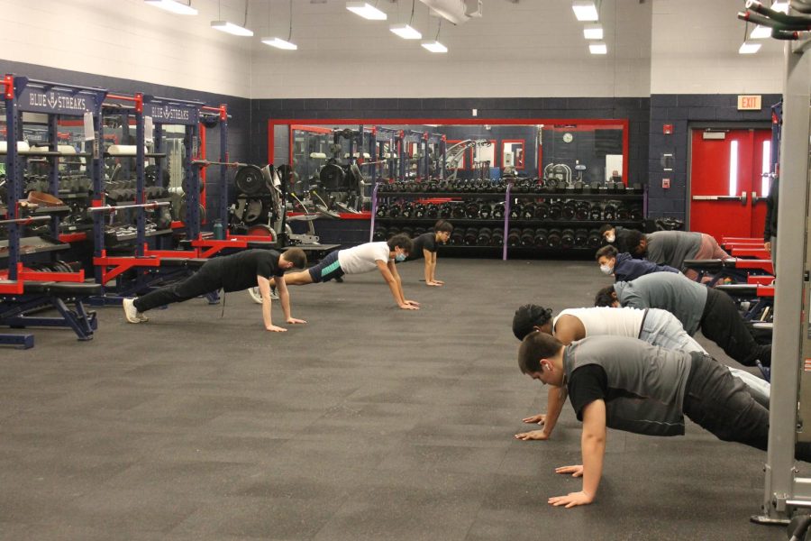 Students in weight training class hold a 45 second plank.