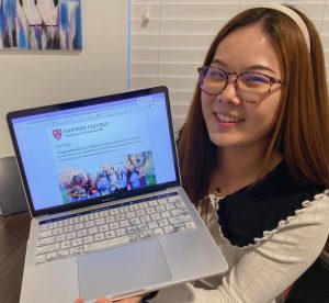 Senior Jeslyn Liu holds up her computer after opening her acceptance letter from Harvard University.