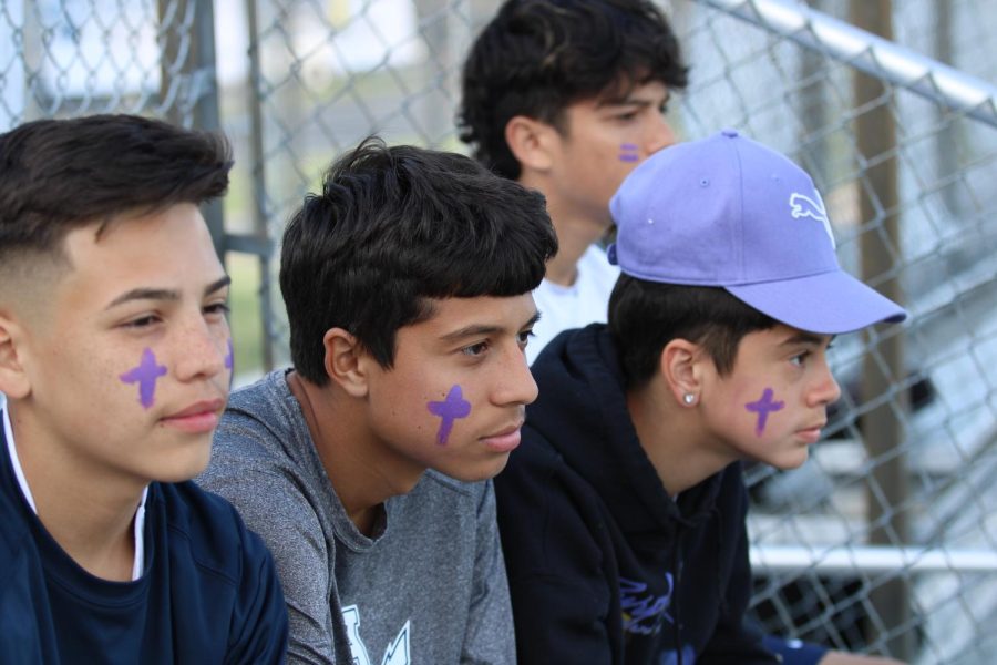 Sophomores Steven Caranza and Daniel Romero sit next to freshman Andres Cardoso and show support for Lena Rasool by wearing purple face paint.