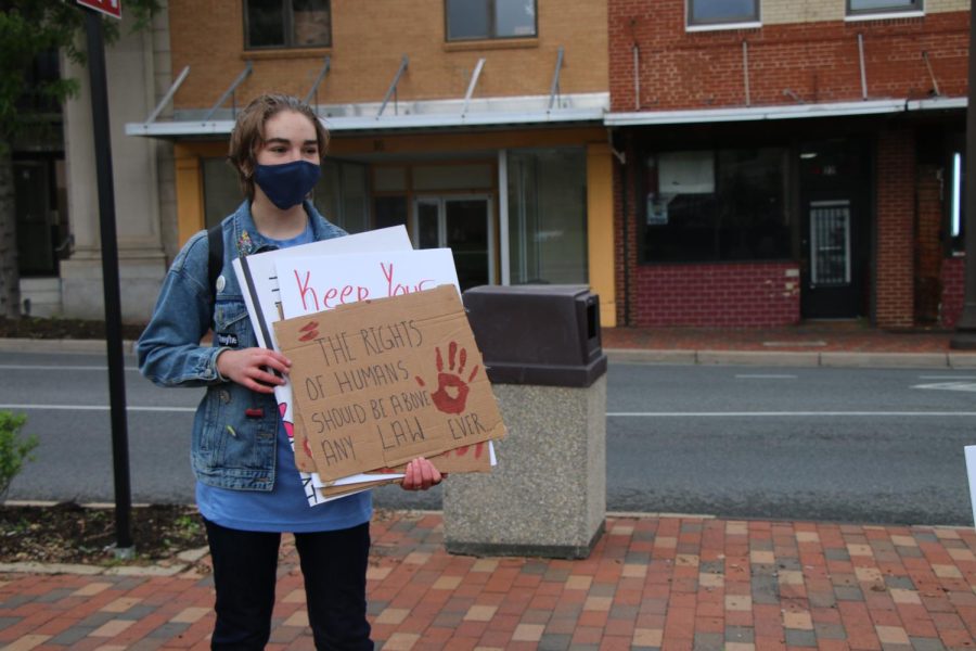 Rowan Whitmeyer holds a protest sign that says the rights of humans should be above any law ever. 