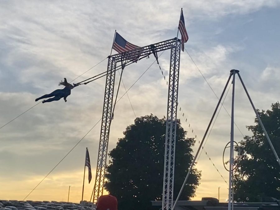 A trapeze artist performs for the fair and spins on the bar without using her hands.