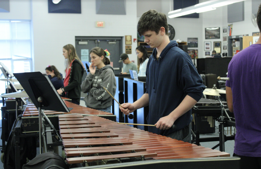A student practices some scales while other students are getting critiques on their playing. 