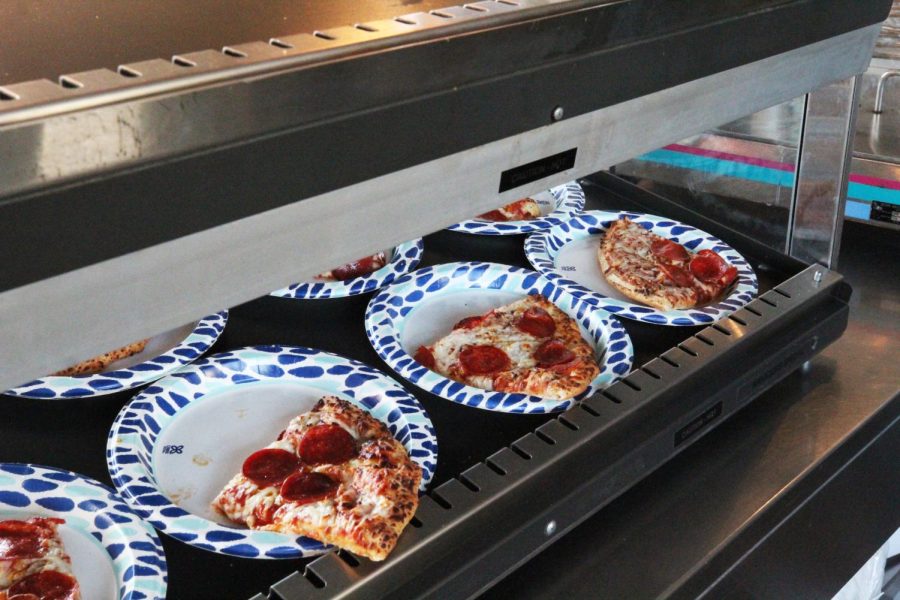 Pepperoni pizza is arranged on a heated display. 
