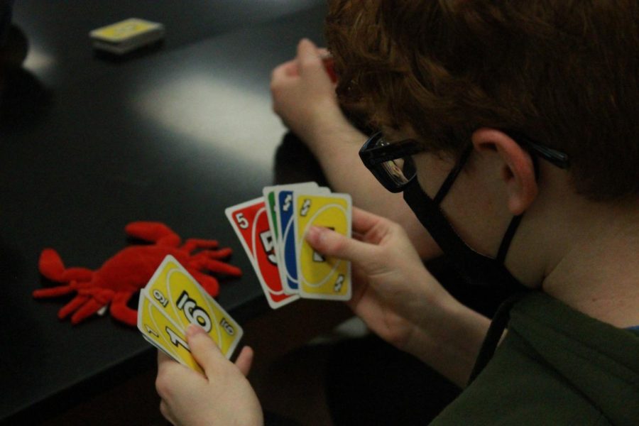 Board game club member looks at his UNO cards. 