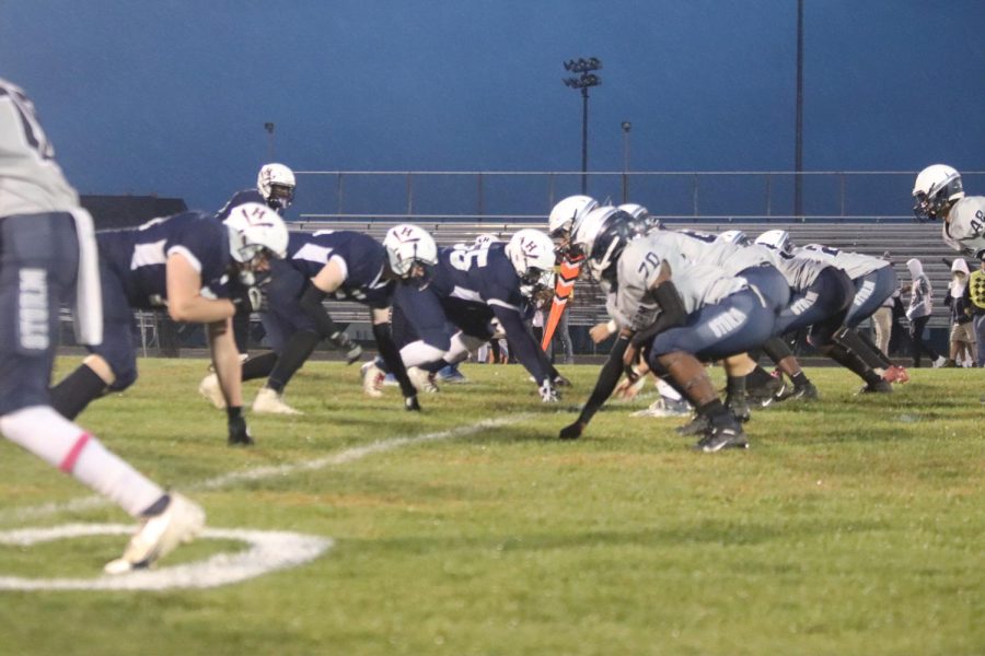 The varsity football team lines up for defense at the 10 yard line. 