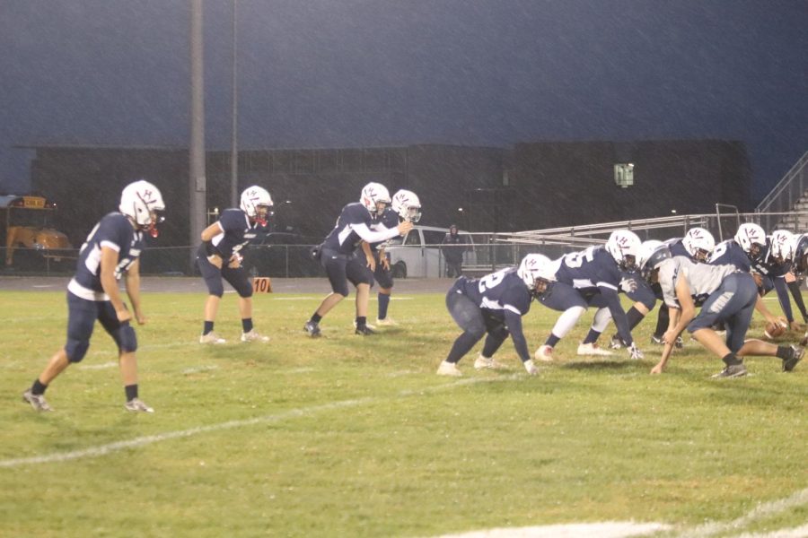 The varsity football team hikes the ball while on offense. 