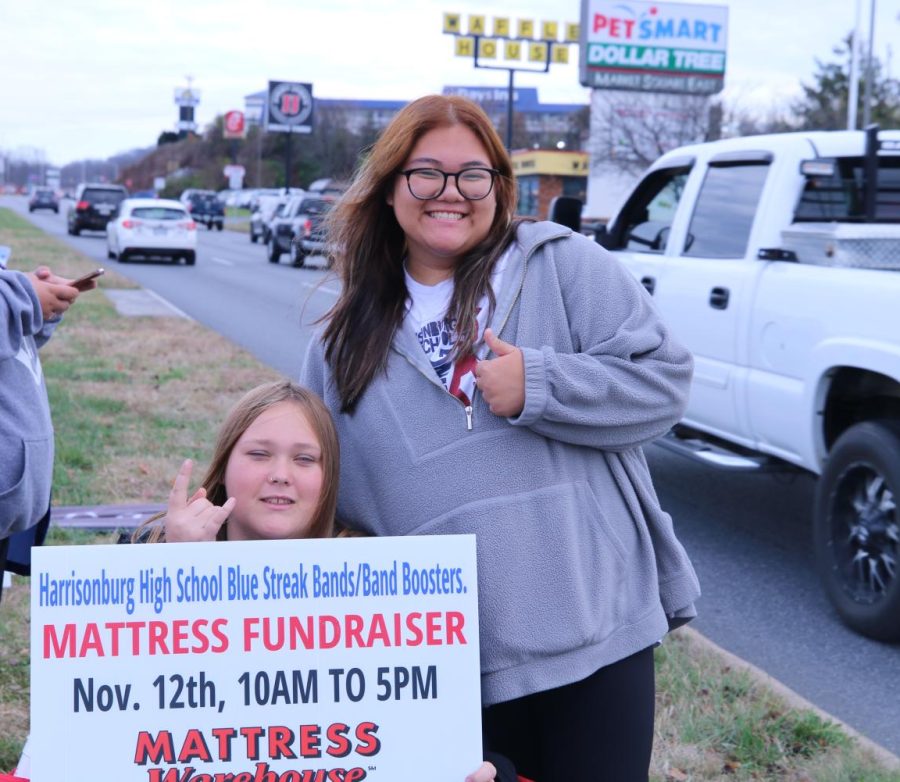 Juniors Kristi Duong and Erika Beck hold signs at the mattress fundraiser. 
