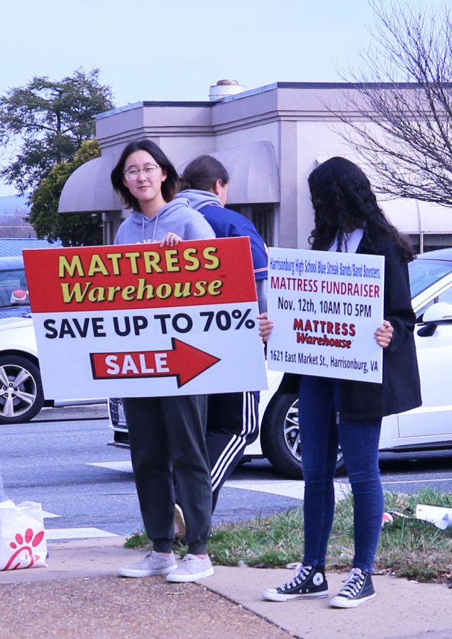 Freshman Leslie Yang encourages passing cars to support the Blue Streak Band Mattress Fundraiser. 