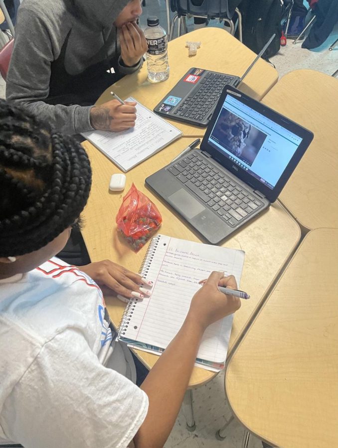Senior Jayla Walker along with Senior Cadren Whitelow taking paper notes being sourced from their teacher. 