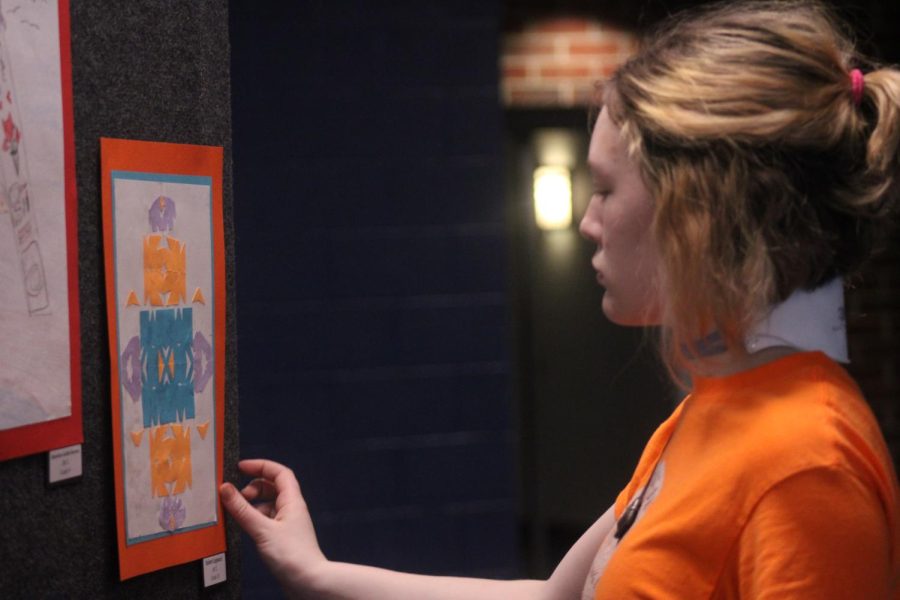 Sophomore Zaida Wang puts up artworks for the art showcase before the musical. People could look at artworks before the performance began and during intermission.