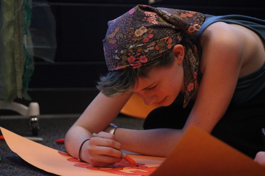 Freshman Wren Hamner does the touch-ups on a sign before the musical begins. 