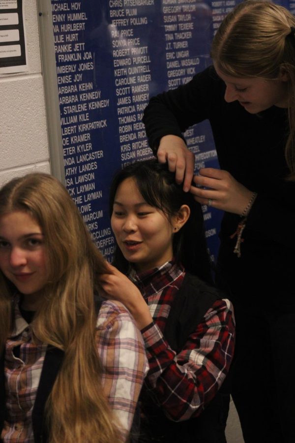Sophomore and assistant stage manager Elaina Jones braids freshman Lya Hurst's hair while Hurst braids Matilda Bunn's hair. Hurst and Bunn are a part of the cast. 