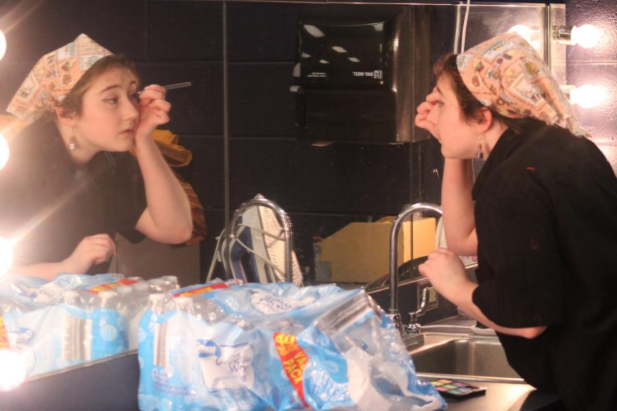 Senior Finn Maddox does their makeup before opening night. They are a part of the costuming team on cast. 