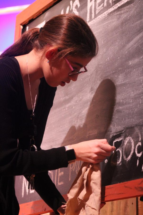 Freshman Emma Loflin prepares the blackboard for opening night. Loflin is a part of crew. 