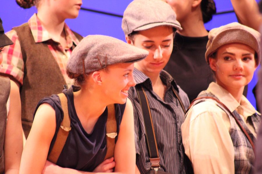 The cast of "Newsies" gathered on a stage for a group photo by photographer Bob Adamek. Junior Natalie Corso talks to her friends while they get ready for the photos. 