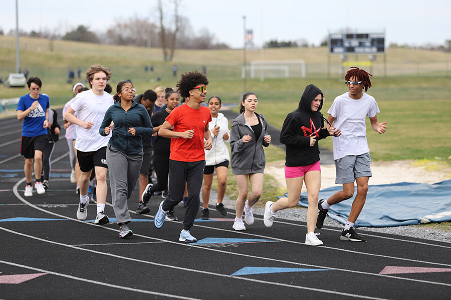 A group of sprinters run a warm-up lap.