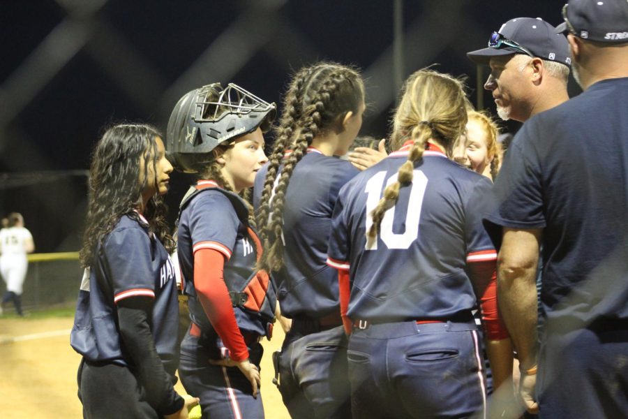 The girls gather around coach Derek Smiley for a huddle after a good inning on the field.  