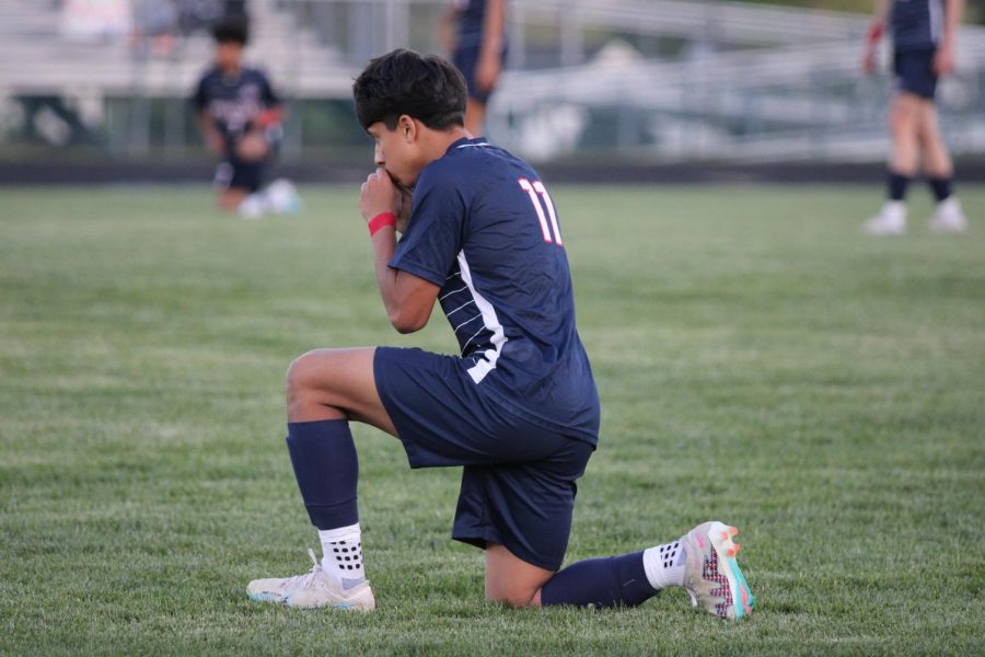 Junior Daniel Romero kneels down, saying quick prayer before game. 