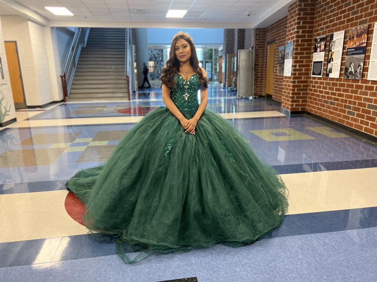 Junior Anay Clemente posing while wearing her green quinceanera dress . 