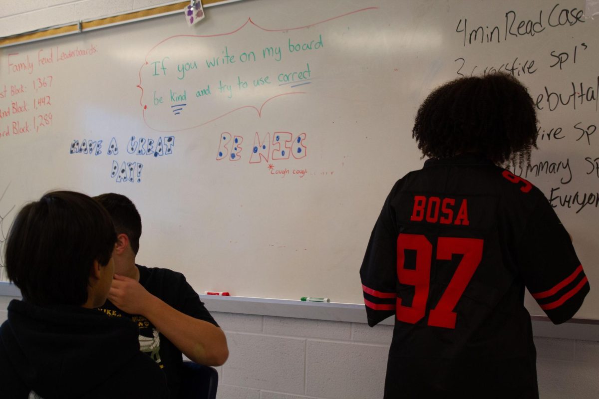 Aiyana Thornton teaching her group and writing on the whiteboard about Debate.