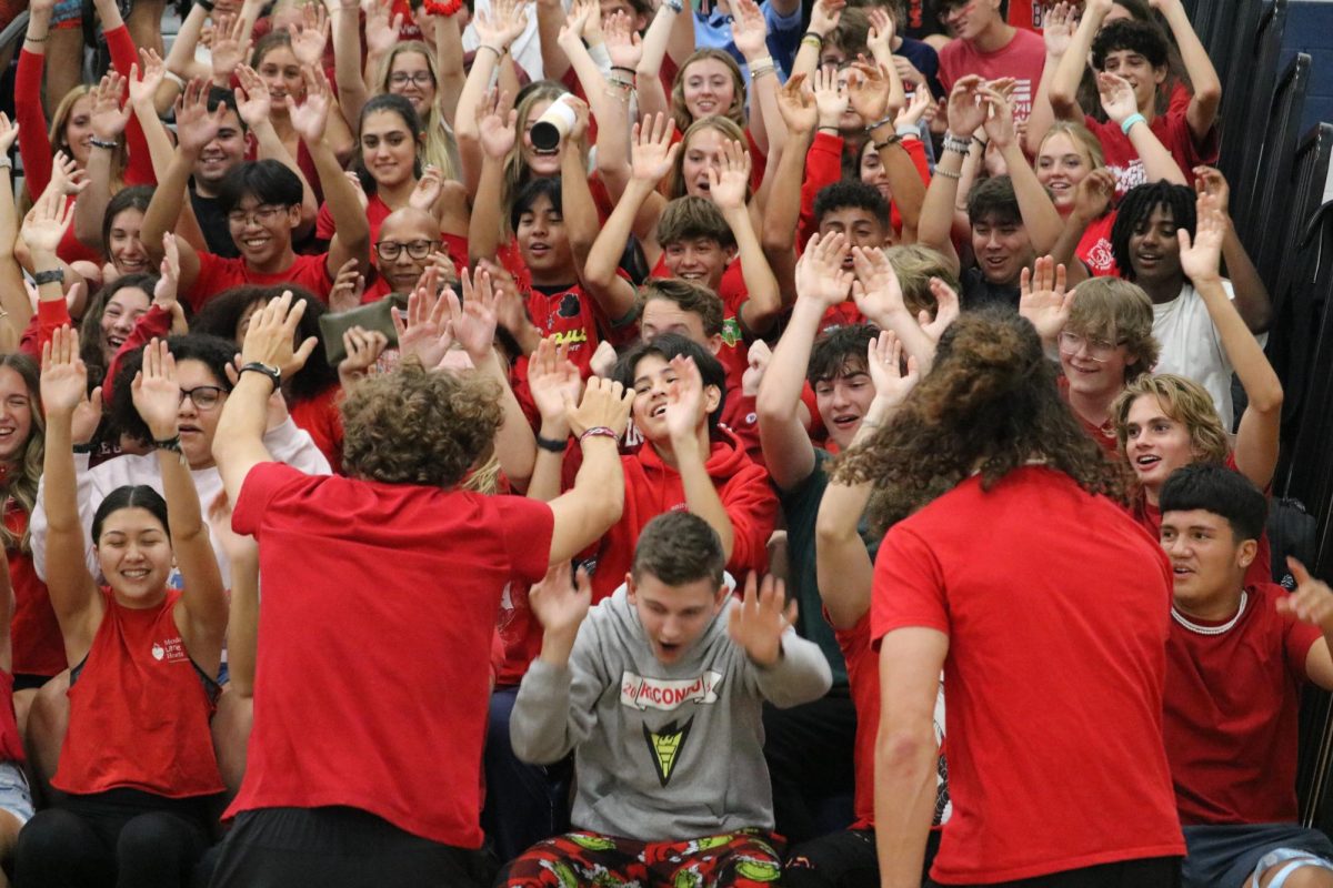 Junior Davis Bert leads the Red Sea in doing the wave through the section. Students shout and cheer for the volleyball team throughout the game. 