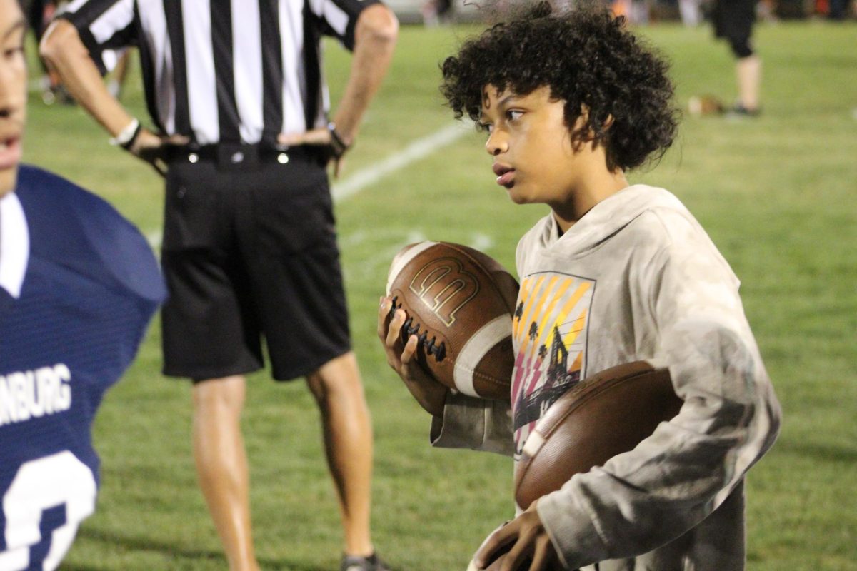 Santana Perrys younger brother Xavier Perry carries balls off the sideline.