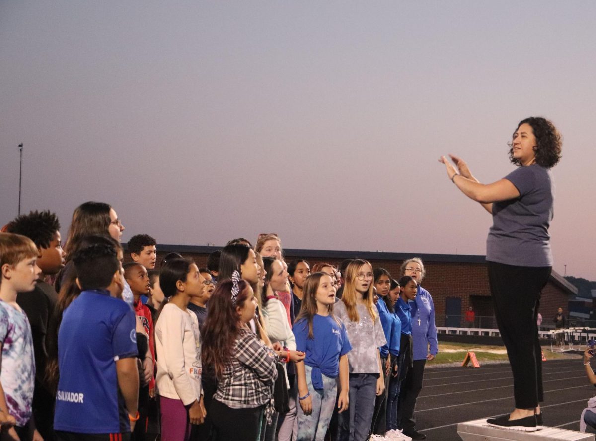 Students from different grades sing the national anthem together before the football game.