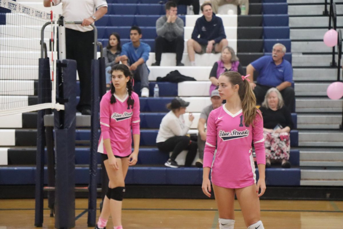 Freshman Sarah Hairston and junior Macy Waid wait for the opposing team to serve.