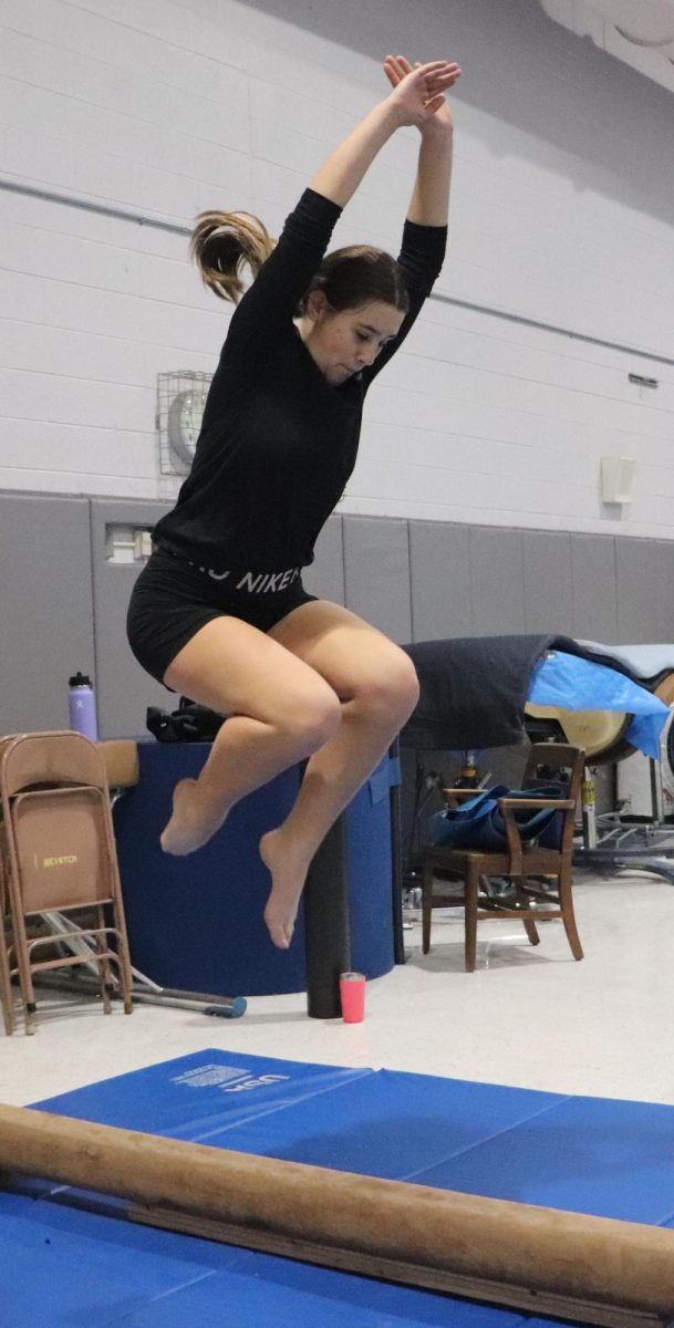 Freshman Jordyn Byler does a tuck jump on the low beam. This is Bylers first year doing gymnastics at the high school. 