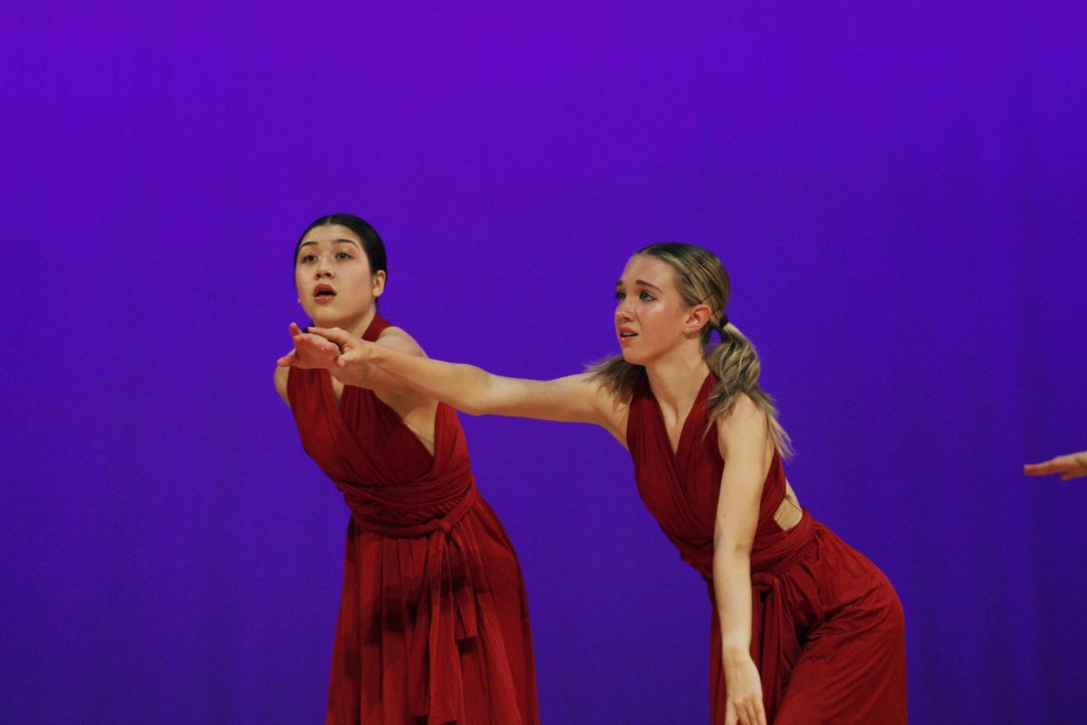 Senior Jade Chao (left) and sophomore Abby Gibson (right) reach their hands out during their performance.