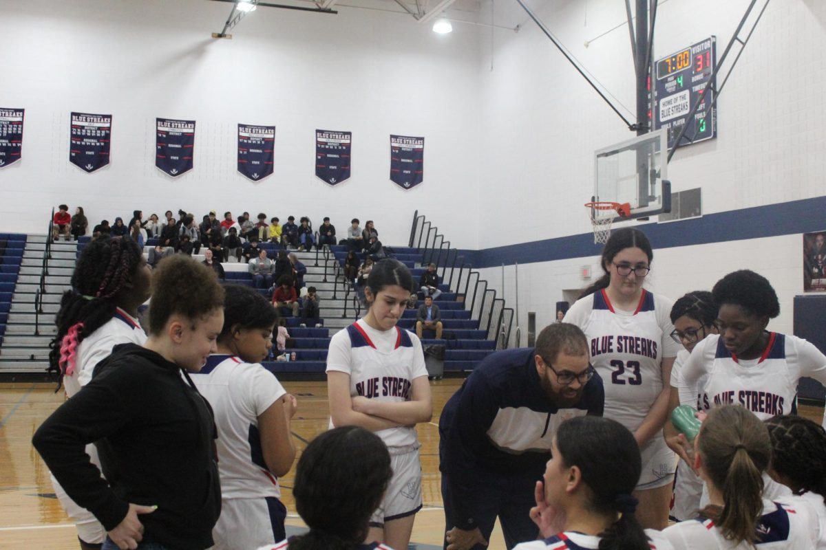 Coach Jared Watson giving the team directions to the team before they get on the court 