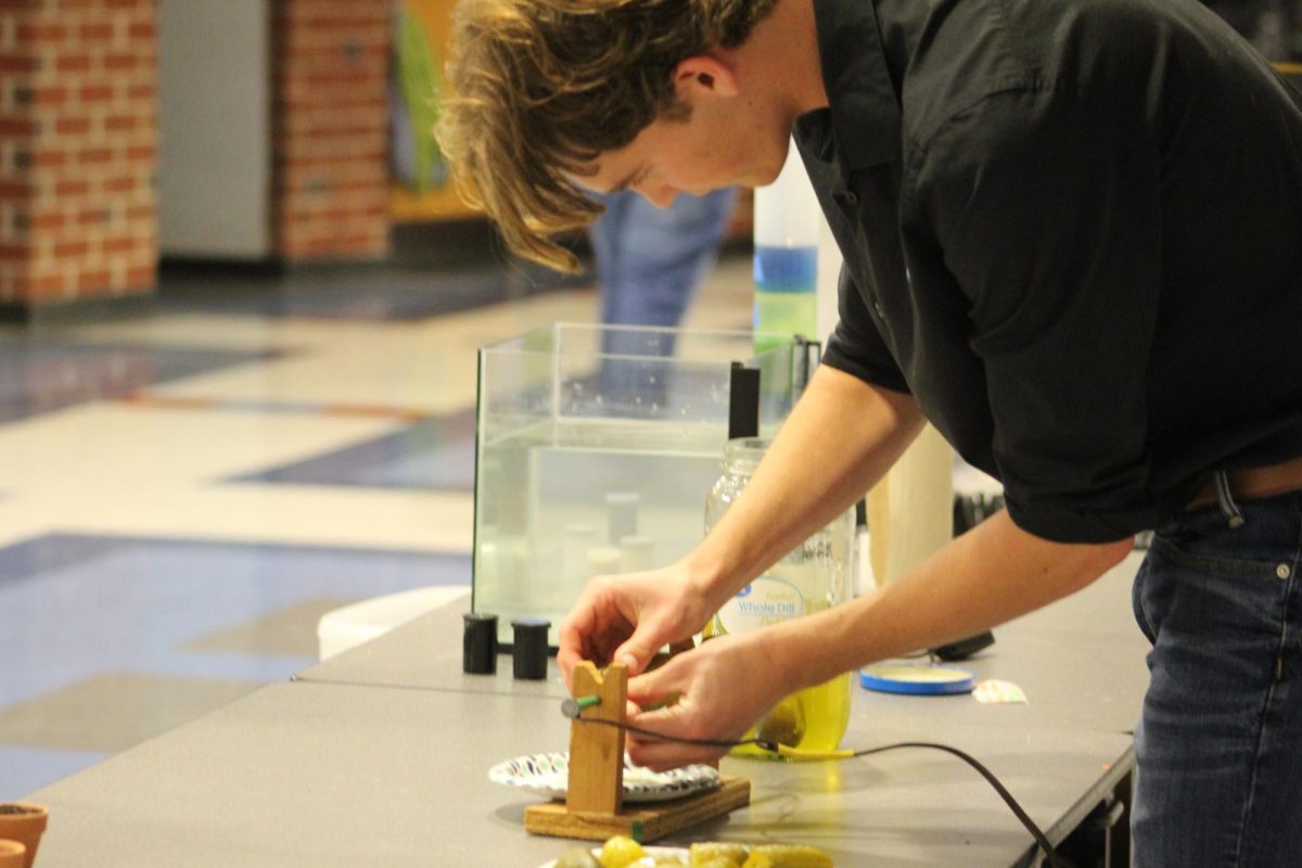 STEM student prepares his station about glowing pickles during STEM night.