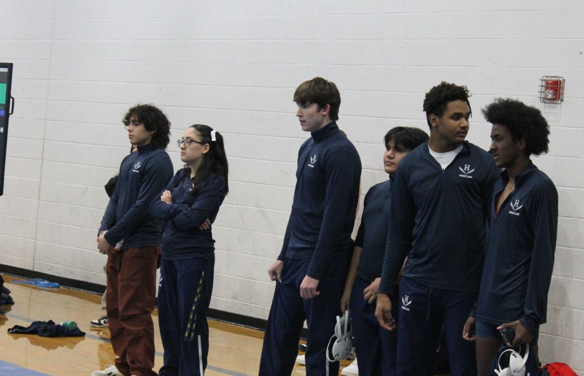 The wrestling team looks on as a teammate wrestles.