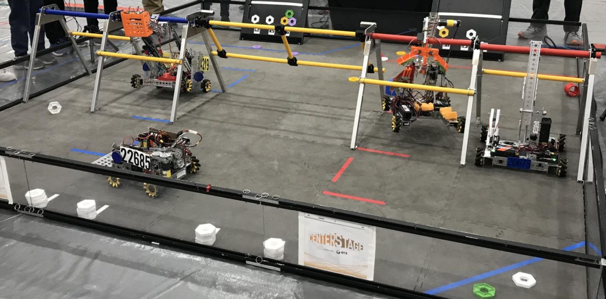 The end of a match, three of the robots are attempting to hang from the colored bars called the rigging.