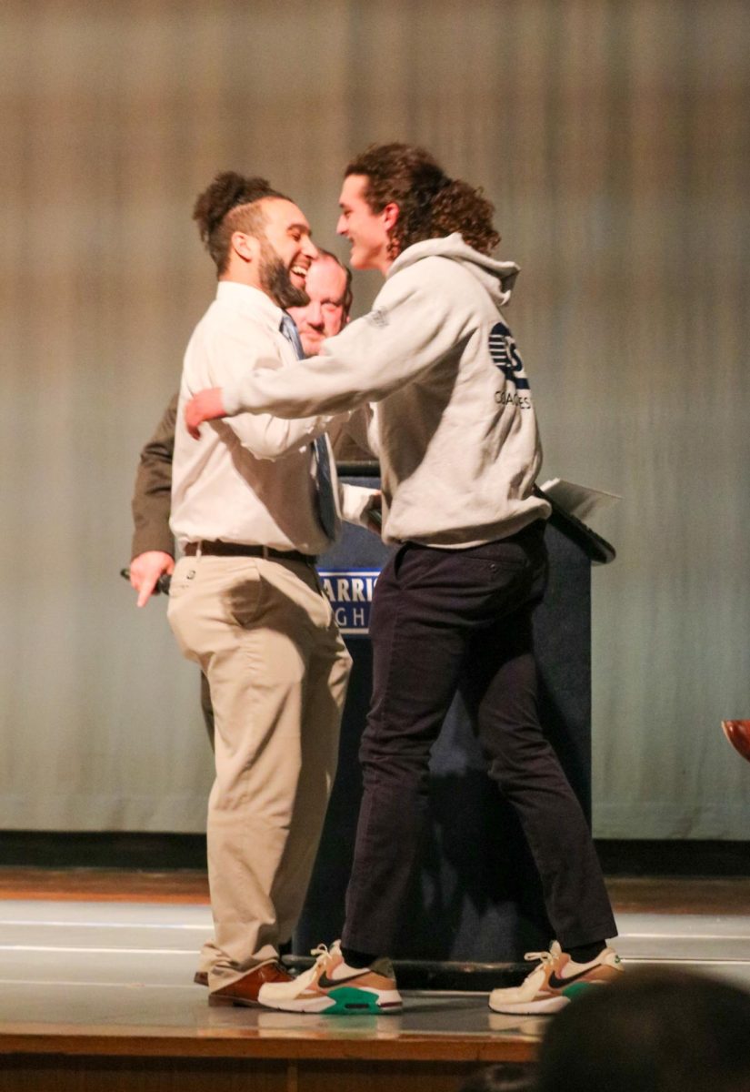 Junior Varsity Coach Curtis Cherebin congratulates senior Jonathan Biller on his award that he received for his football season. 