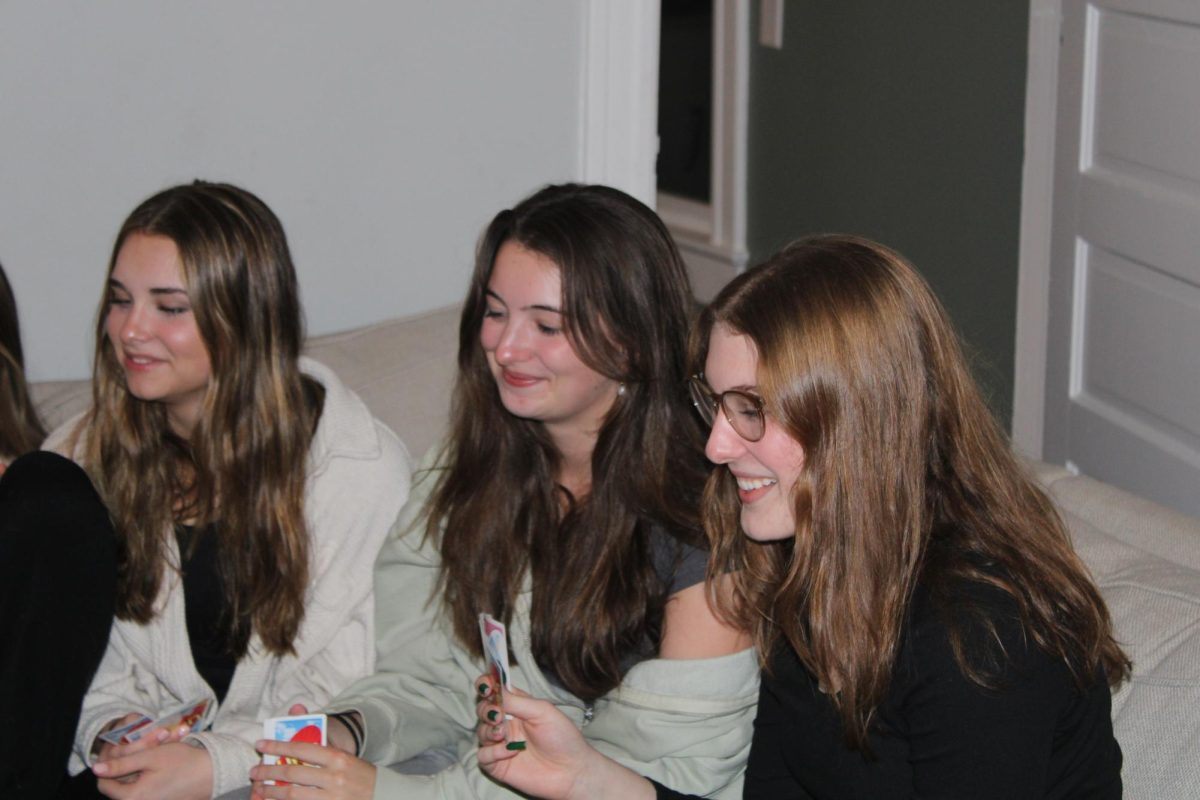 Seniors Marin Sikes and Delaney Shaver and Freshman Maeve Scherpereel wait for their turn in Uno. 	