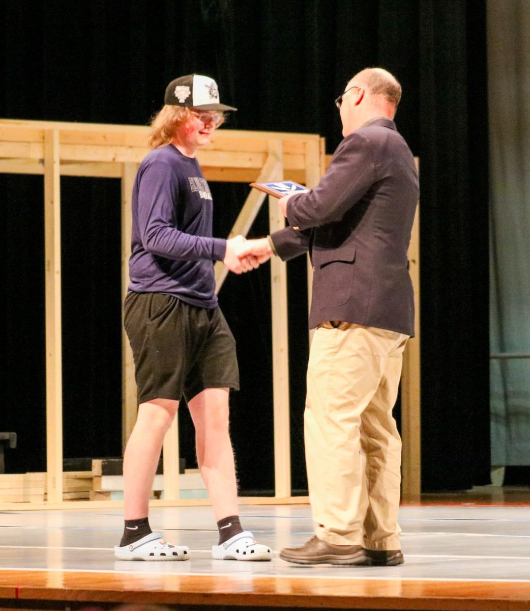 Golf coach Chris Sorber hands junior Drew Lankford an award. 