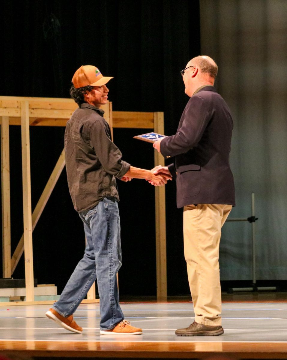 Golf coach Chris Sorber hands junior Javier Molina an award. 