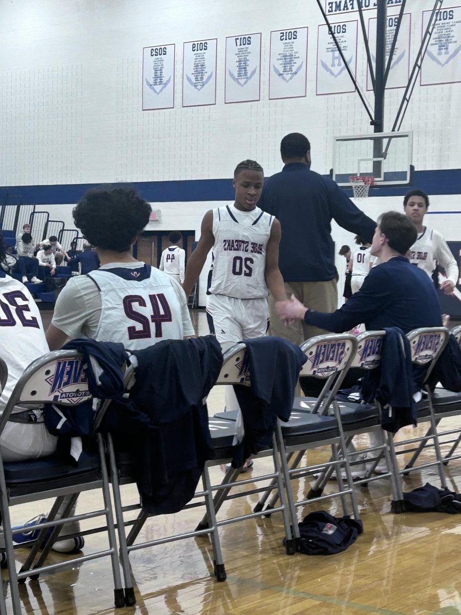 Freshman Kenyon Benton is congratulated by teammates and coach after coming off the court.