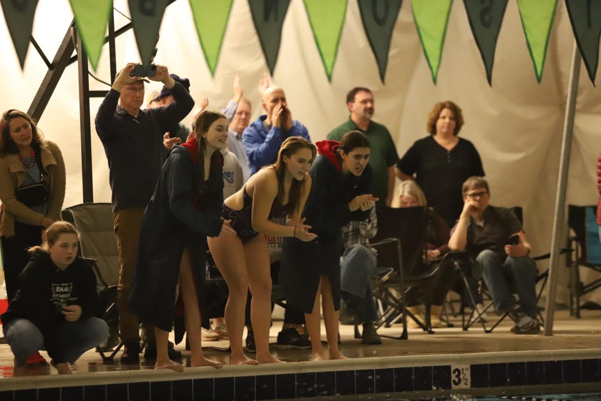 Girls swim team cheer on teammates in race.