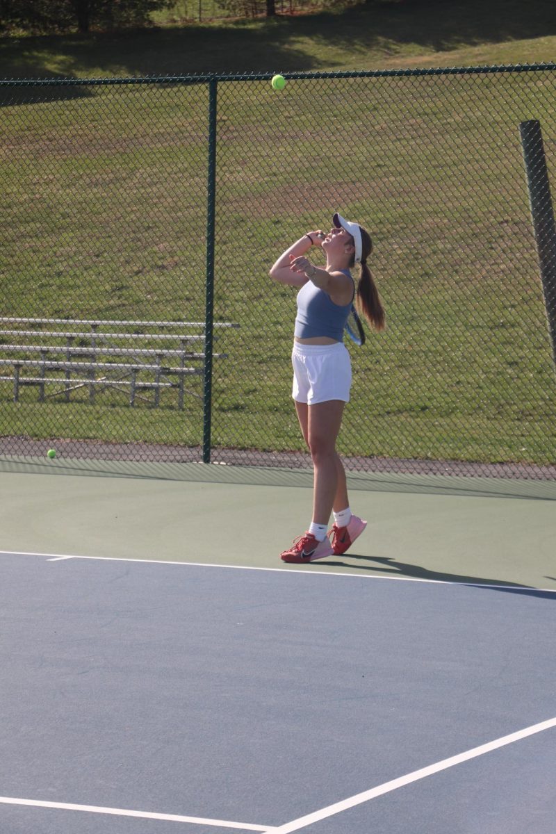 Junior Evelyn Lewis warms up her serve for a doubles match during practice. 