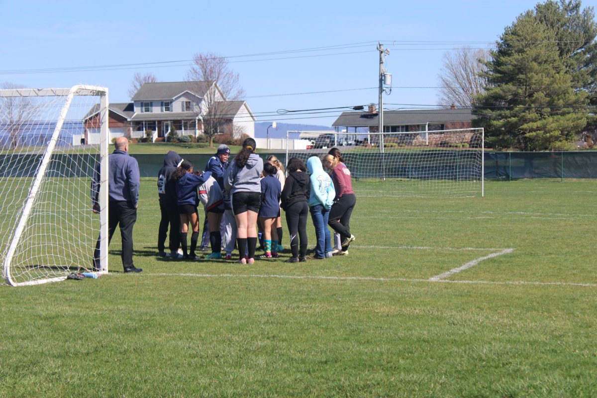 Jv girls soccer huddles as a team before practice.